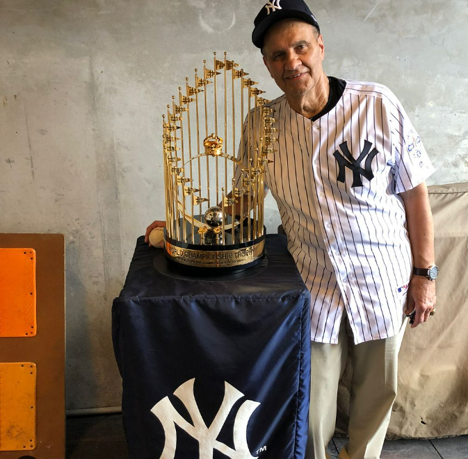 Joe Torre poses with a World Series trophy won by the Yankees during his time as their manager.