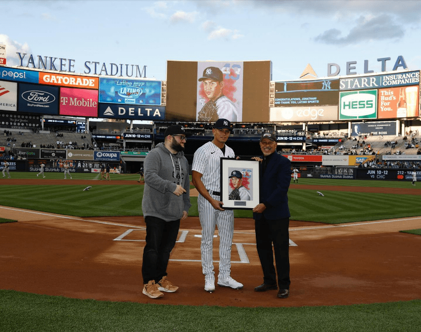 Dos aficionados presentan a Jonathan Loaisiga un boceto del lanzador de los Yankees en el Yankee Stadium.
