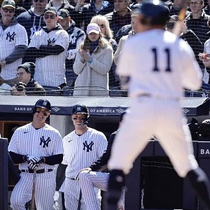 Anthony Volpe bats as Aaron Judge and Anthony Rizzo look at him.