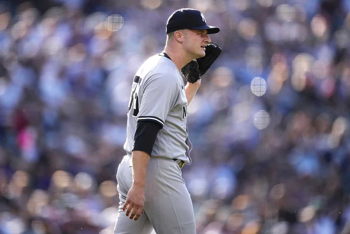 New York Yankees starting pitcher Clarke Schmidt asks for an explanation from umpires after being called for a balk, which scored a run, during the first inning of the team's baseball game against the Colorado Rockies on Saturday, July 15, 2023, in Denver.