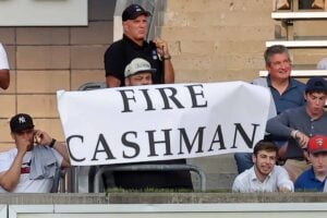 Yankees fan Jon stands holding "FIRE CASHMAN" sign on August 2, 2023, outside Yankee Stadium.