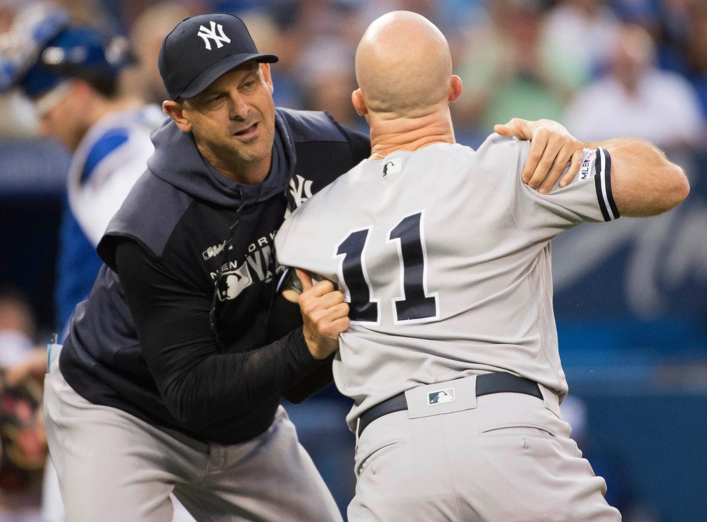 Yankees manager Brian Cashman stops Brett Gardner, who is charging toward the umpire, at