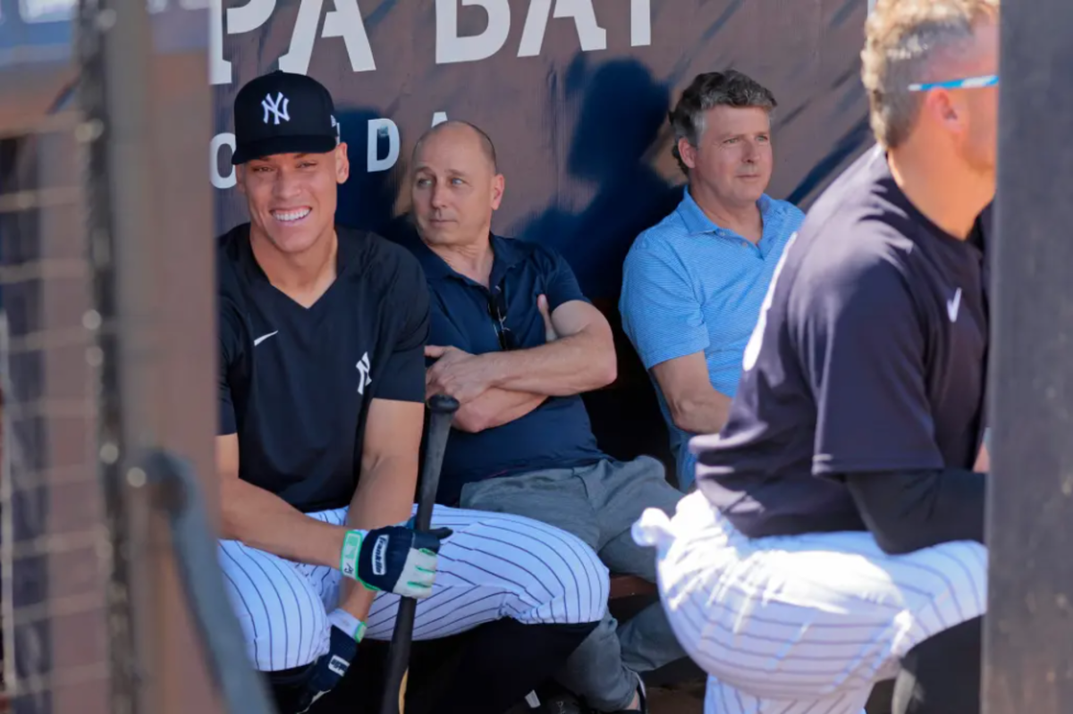 El capitán de los Yankees Aaron Judge está con el GM Brian Cashman y el propietario Hal Steinbrenner.