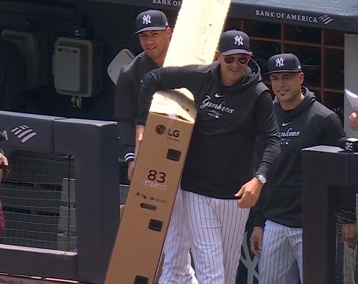 Gleyber Torres and Aaron Boone carry a TV to be presented to John Sterling during his farewell at Yankee Stadium on April 20, 2024.