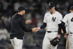 New York Yankees pitcher Clay Holmes, second from left, hands the ball to manager Aaron Boone, left, as he leaves during the ninth inning of a baseball game against the Seattle Mariners, Monday, May 20, 2024, in New York.