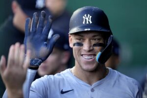 New York Yankees’ Aaron Judge celebrates in the dugout after scoring on sacrifice fly hit by Anthony Rizzo during the first inning of a baseball game against the Kansas City Royals Wednesday, June 12, 2024, in Kansas City, Mo.