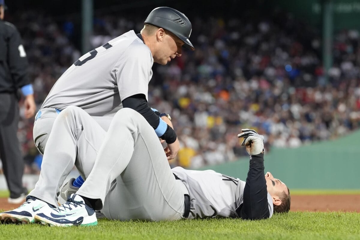 New York Yankees first base coach Travis Chapman, left, tends to Anthony Rizzo, right, following a first base collision in the seventh inning of a baseball game against the Boston Red Sox, Sunday, June 16, 2024, in Boston. Rizzo left the game after colliding with Red Sox pitcher Brennan Bernardino on a play at first and falling hard on his right wrist.