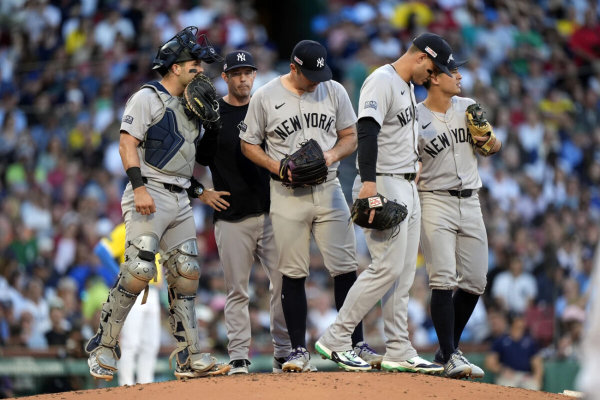 New York Yankees pitcher Carlos Rodón, center, looks down during a meeting at the mound during the first inning of the team’s baseball game against the Boston Red Sox on Saturday, June 15, 2024, in Boston.