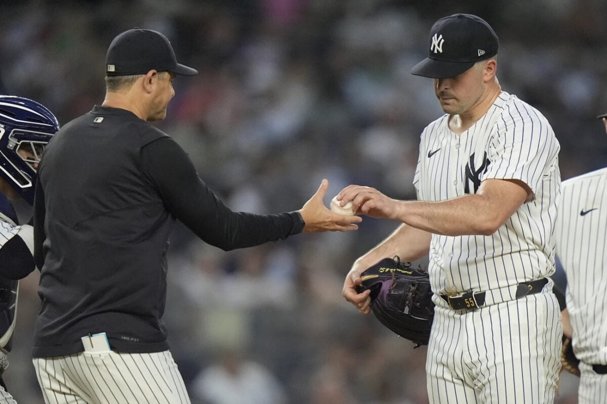 New York Yankees pitcher Carlos Rodón, right, hands the ball to manager Aaron Boone during the fourth inning of the team’s baseball game against the Atlanta Braves, Friday, June 21, 2024, in New York.