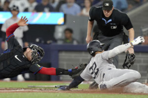 New York Yankees' Juan Soto (22) scores past Toronto Blue Jays catcher Danny Jansen during the fourth inning of a baseball game Friday, June 28, 2024, in Toronto.