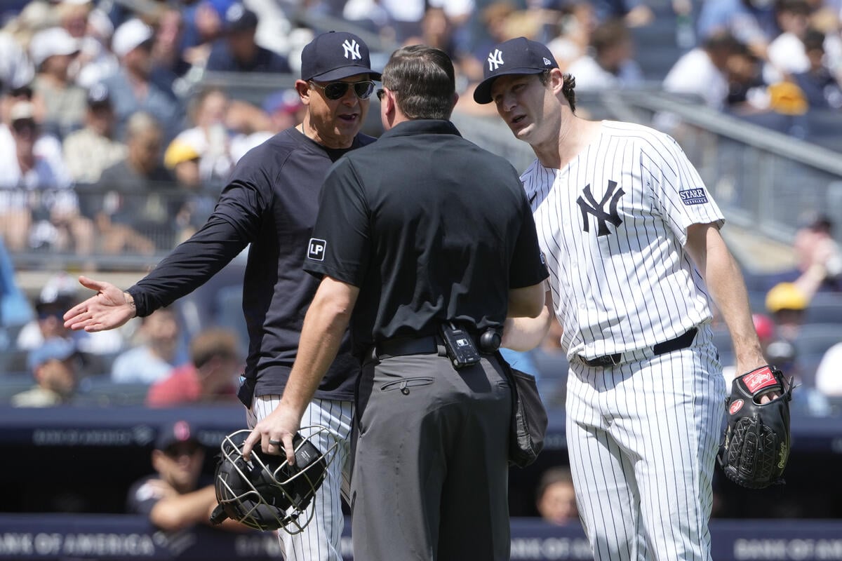 New York Yankees manager Aaron Boone, left, and pitcher Gerrit Cole, right, talk to an umpire, center, during the second inning of a baseball game against the Cleveland Guardians, Thursday, Aug. 22, 2024, in New York.