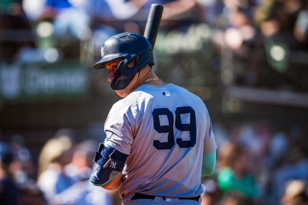 Aaron Judge, positioned at the back, turns his head to the left to listen to instructions from the Yankees' coaching staff. His expression remains focused as he prepares for the final stretch of the season.