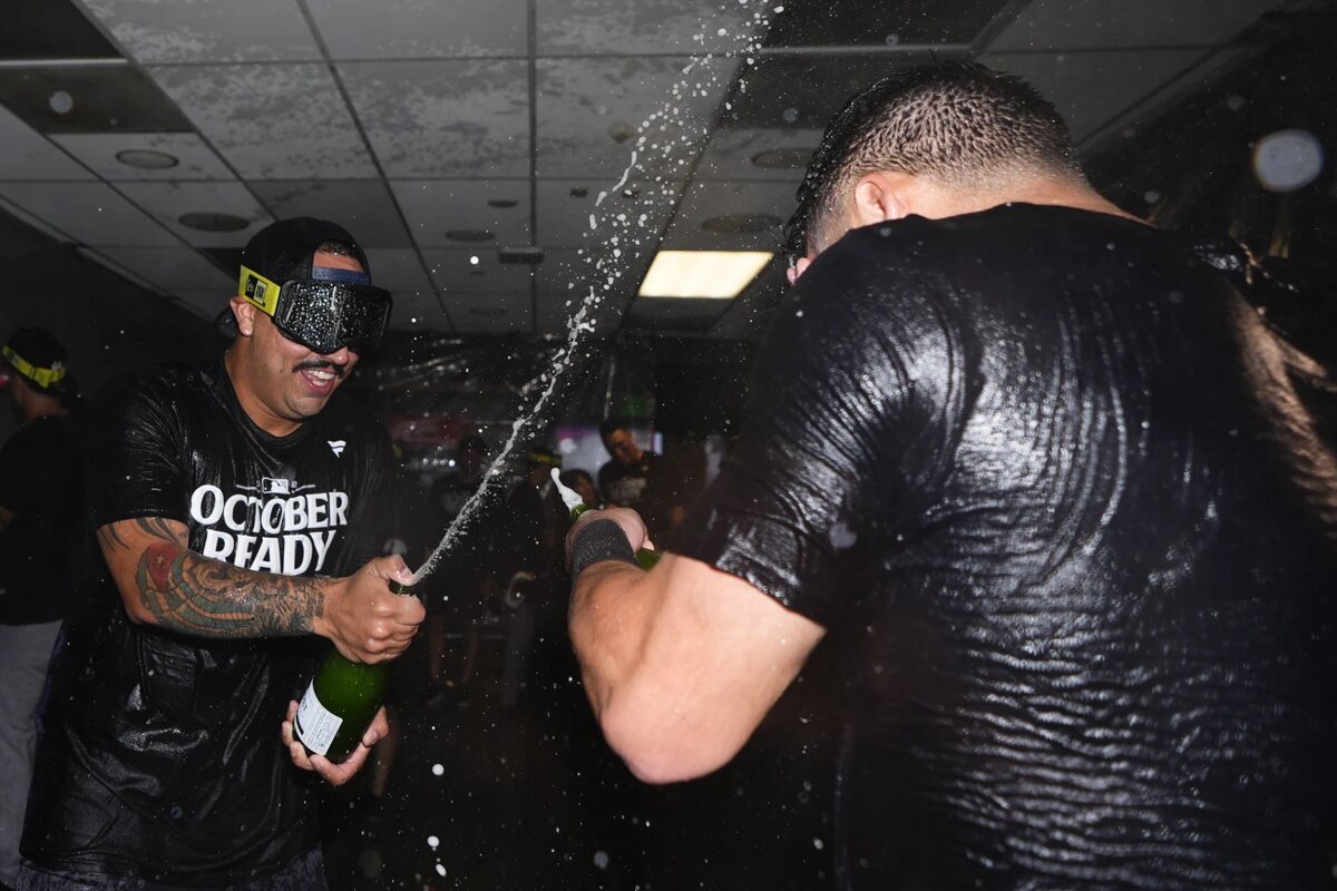 New York Yankees starting pitcher Nestor Cortes, left, sprays champagne on a teammate as they celebrate clinching a playoff spot after a 2-1 win in 10 innings over the Seattle Mariners in a baseball game Wednesday, Sept. 18, 2024, in Seattle.