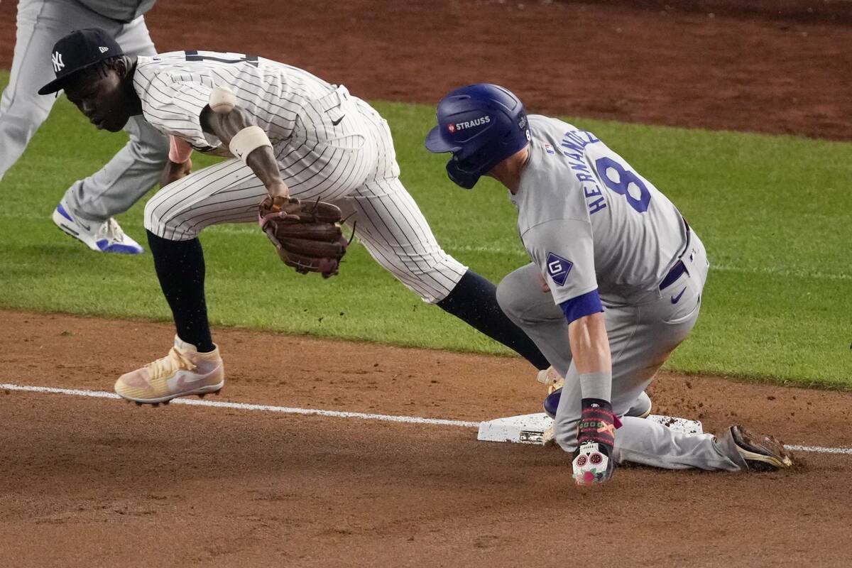 Kiké Hernández (derecha), de los Dodgers de Los Ángeles, está a salvo en la tercera base cuando Jazz Chisholm Jr., tercera base de los Yankees de Nueva York, espera el lanzamiento del campocorto Anthony Volpe durante la quinta entrada del quinto partido de las Series Mundiales de béisbol, el miércoles 30 de octubre de 2024, en Nueva York. Volpe cometió un error de lanzamiento.   