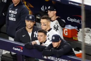 Yankees players Giancarlo Stanton, Aaron Judge, Anthony Volpe, and DJ LeMahieu react from the dugout fence during the ninth inning of World Series Game 3 on October 28, 2024.