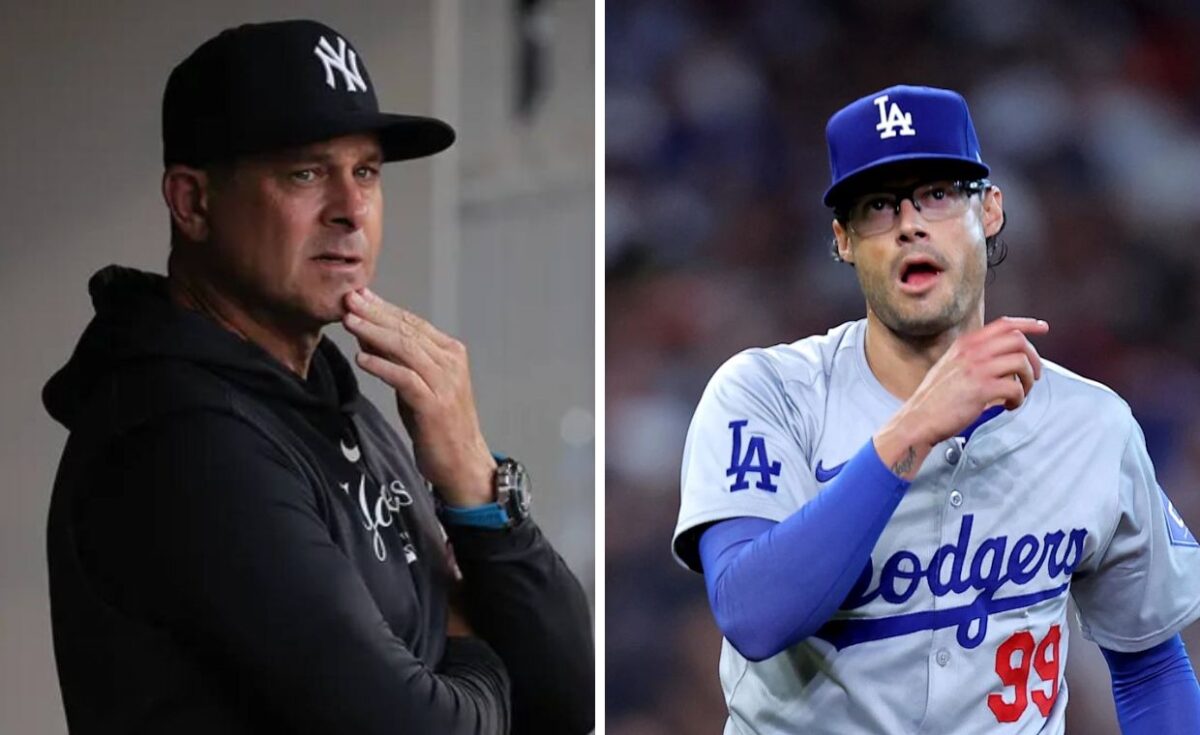 Yankees manager Aaron Boone stands on the left, wearing the Yankees' official cap and jacket, appearing focused, as though watching a game. On the right is Joe Kelly, dressed in the Dodgers' uniform,