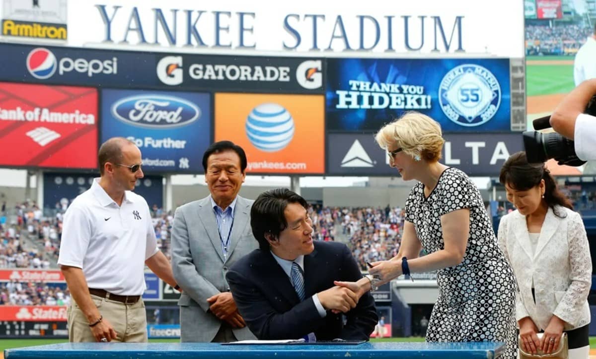 Yankees AGM Jean Afterman congratulates Hideki Matsui after signing retirement papers in 2013 at Yankee Stadium.