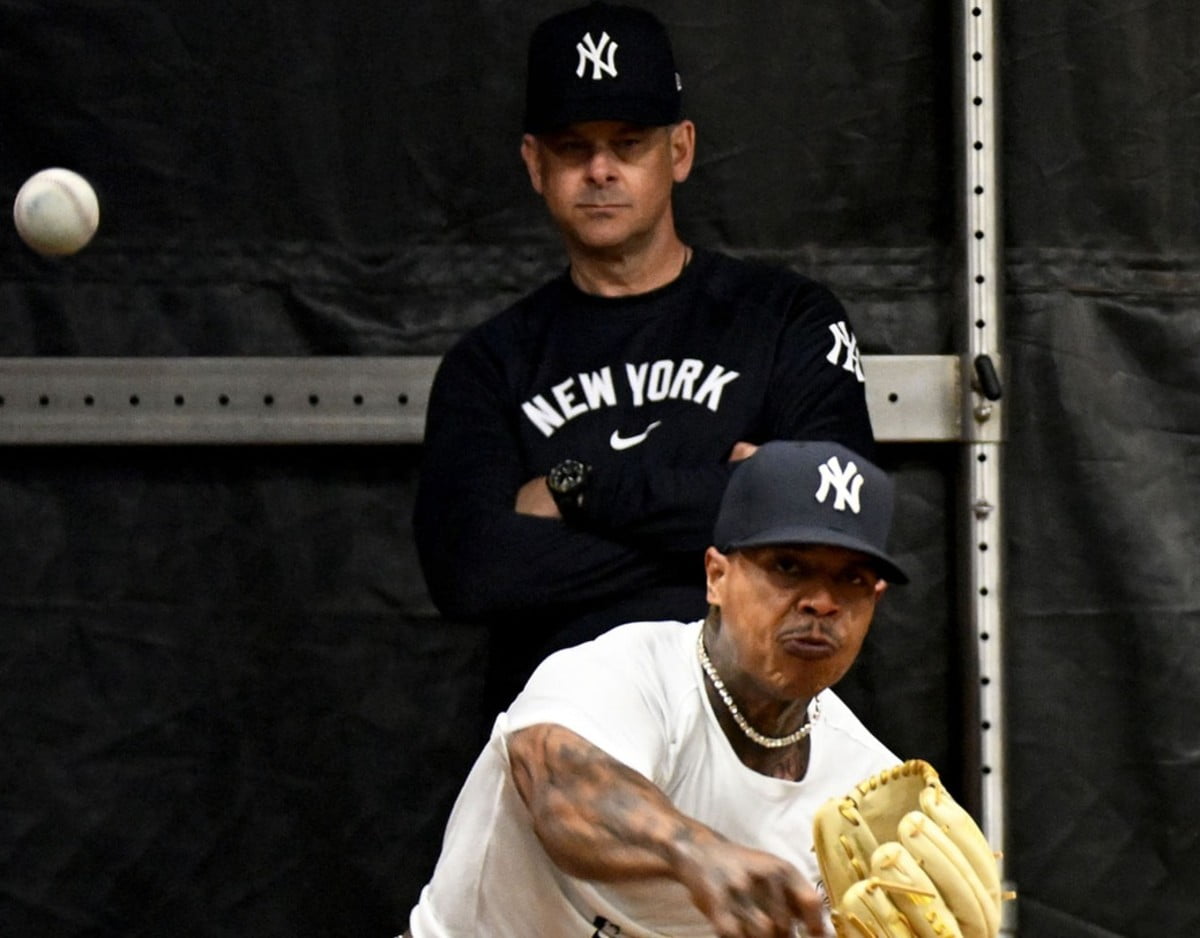 Marcus Stroman throws as the Yankees' manager Aaron Boone looks on.