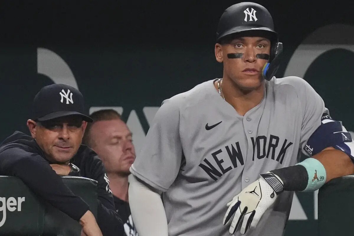 Aaron Judge, de los Yankees de Nueva York, a la derecha, y el entrenador Aaron Boone miran desde el banquillo durante la sexta entrada de un partido de béisbol contra los Rangers de Texas, el martes 5 de agosto de 2025, en Arlington, Texas.