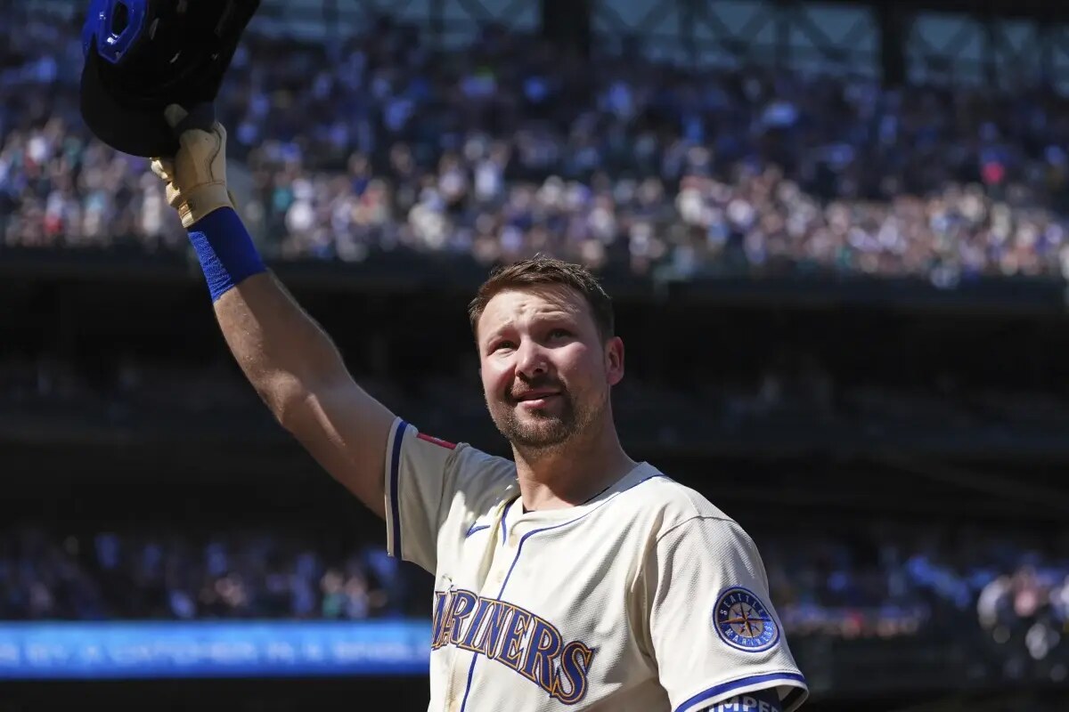 Seattle Mariners’ Cal Raleigh waves his helmet to the crowd during an ovation after hitting a two-run home run against the Athletics during the second inning of a baseball game, breaking the record for single-season home runs by a catcher at 49, Sunday, Aug. 24, 2025, in Seattle.