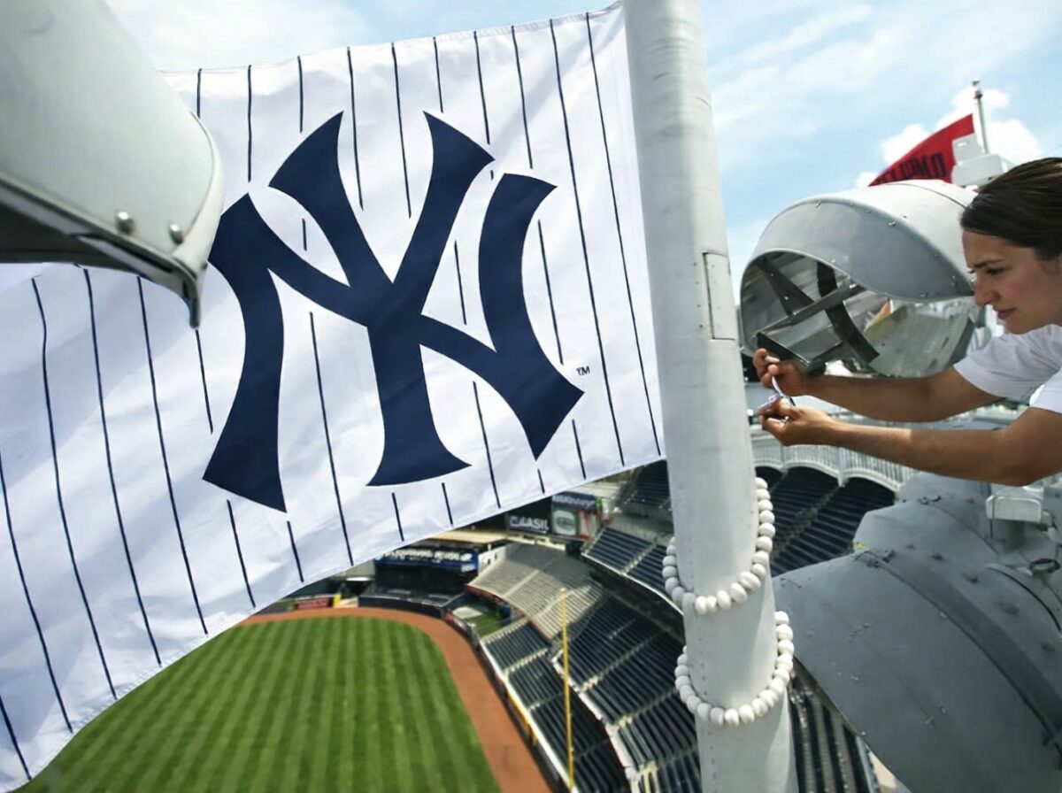 A worker puts a Yankees flag on a pole in Yankee Stadium, 2026.