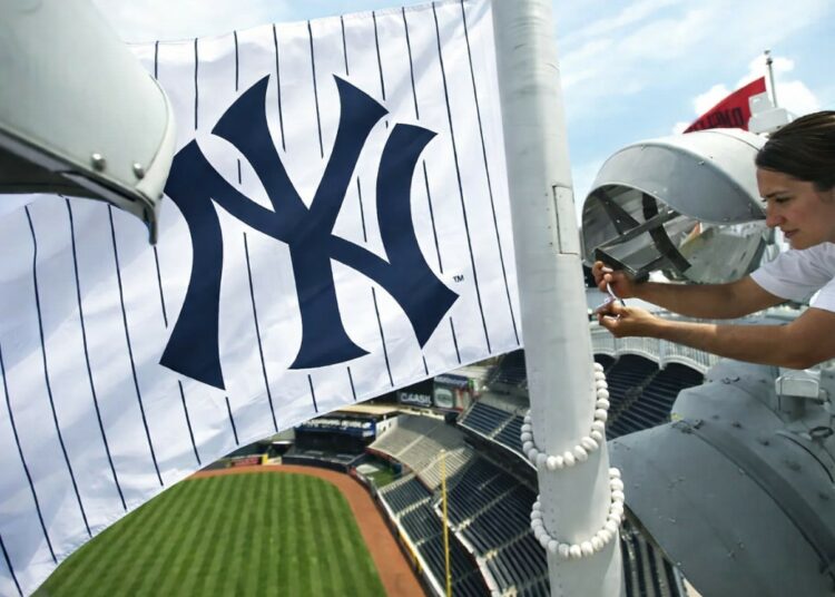 A worker puts a Yankees flag on a pole in Yankee Stadium, 2026.