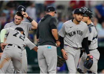 New York Yankees starting pitcher Elmer Rodriguez, right front, walks to the dugout after turning the ball over to manager Aaron Boone, center left, as José Caballero (72), Ben Rice, left rear, and J.C. Escarra, right rear, stand on the mound in the fifth inning of a baseball game against the Texas Rangers Wednesday, April 29, 2026, in Arlington, Texas.