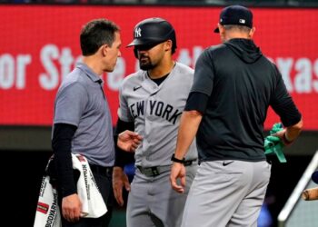 New York Yankees’ Jasson Dominguez, center, talks with a team trainer as manager Aaron Boone, right, looks on after Dominguez was hit by a pitch in the fourth inning of a baseball game against the Texas Rangers Wednesday, April 29, 2026, in Arlington, Texas.