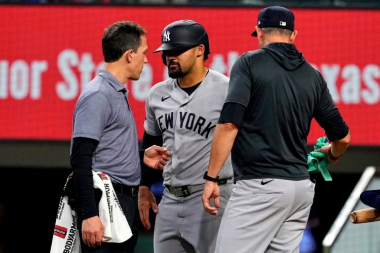 New York Yankees’ Jasson Dominguez, center, talks with a team trainer as manager Aaron Boone, right, looks on after Dominguez was hit by a pitch in the fourth inning of a baseball game against the Texas Rangers Wednesday, April 29, 2026, in Arlington, Texas.