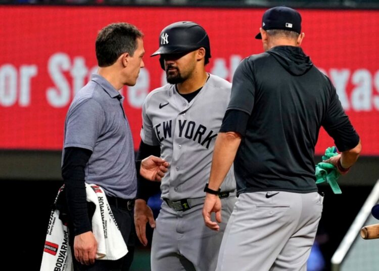 New York Yankees’ Jasson Dominguez, center, talks with a team trainer as manager Aaron Boone, right, looks on after Dominguez was hit by a pitch in the fourth inning of a baseball game against the Texas Rangers Wednesday, April 29, 2026, in Arlington, Texas.