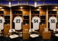 An image of the Yankees clubhouse at New York's Yankee Stadium with Judge, Fried, Rodon, and Stanton jerseys, 2026.